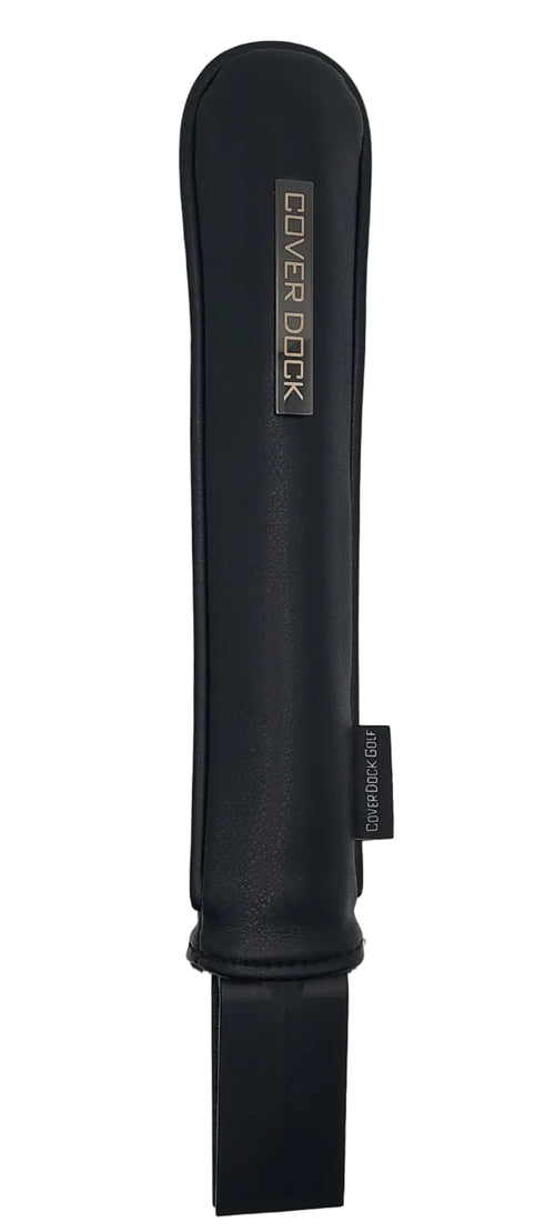 A black protective dock sleeve with a silver metallic 'COVER DOCK' logo plaque on the left side and a black elastic strap extending from the right. The product is photographed horizontally on a plain light gray background.